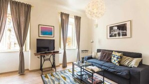 Una sala de estar con un sofá, una mesa de centro, televisor y obras de arte en las paredes.