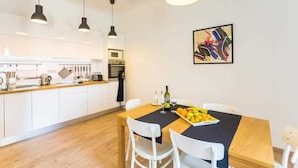 Una cocina moderna con armarios blancos, encimera de madera y un comedor con mantel negro.