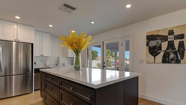 A modern kitchen with stainless steel appliances, a dark wooden island, and a vase of yellow flowers. - ☆Scottsdale Serenity☆ with big pool, putting green and HOT TUB (Scottsdale)
