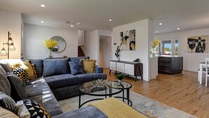 A modern living room with a sofa, coffee table, and a dining area with a kitchen counter. - ☆Scottsdale Serenity☆ with big pool, putting green and HOT TUB (Scottsdale)