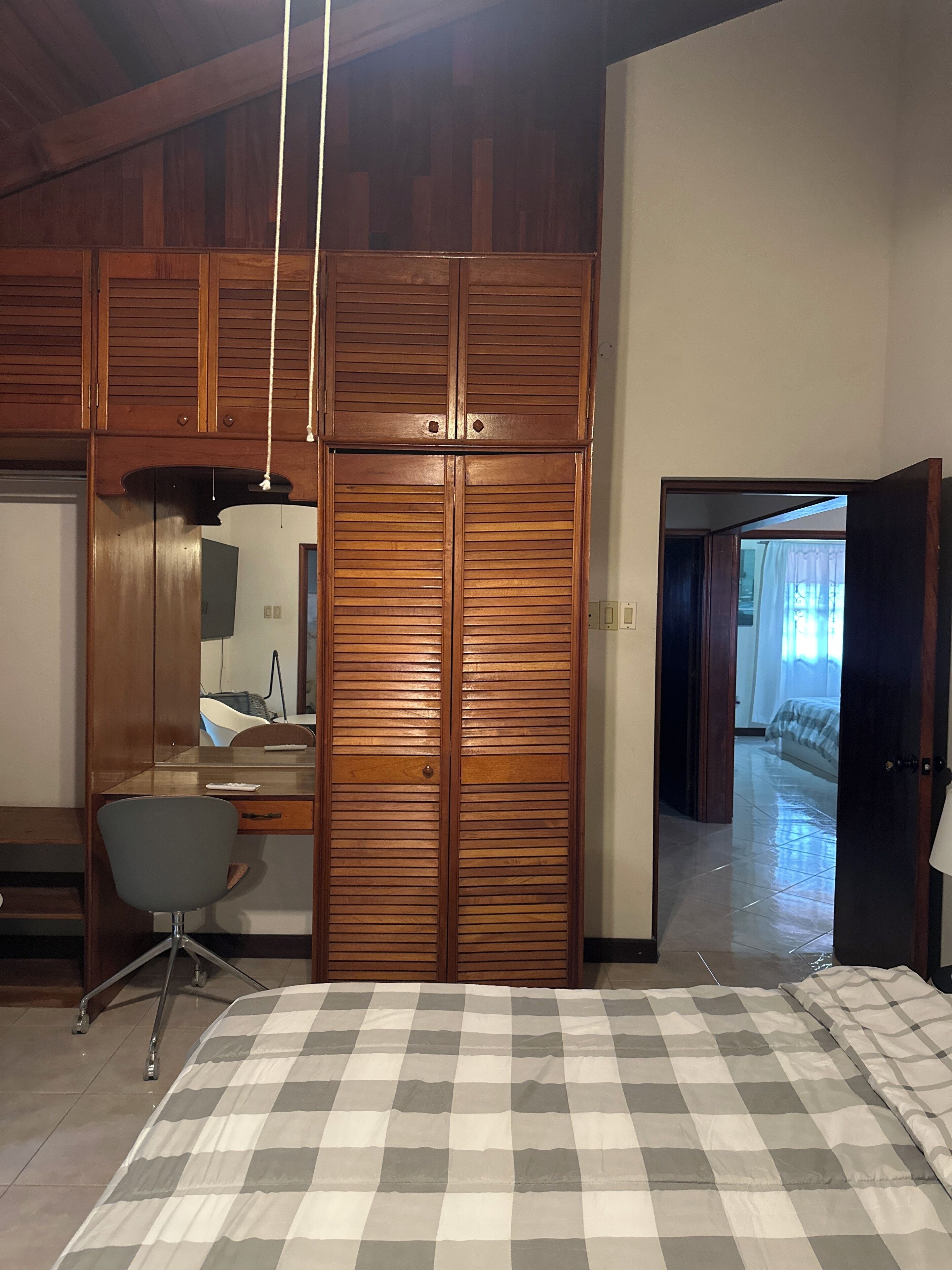 Un dormitorio con colcha a cuadros, armario de madera y un escritorio con silla.