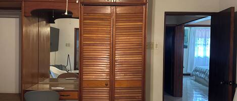 Un dormitorio con colcha a cuadros, armario de madera y un escritorio con silla.