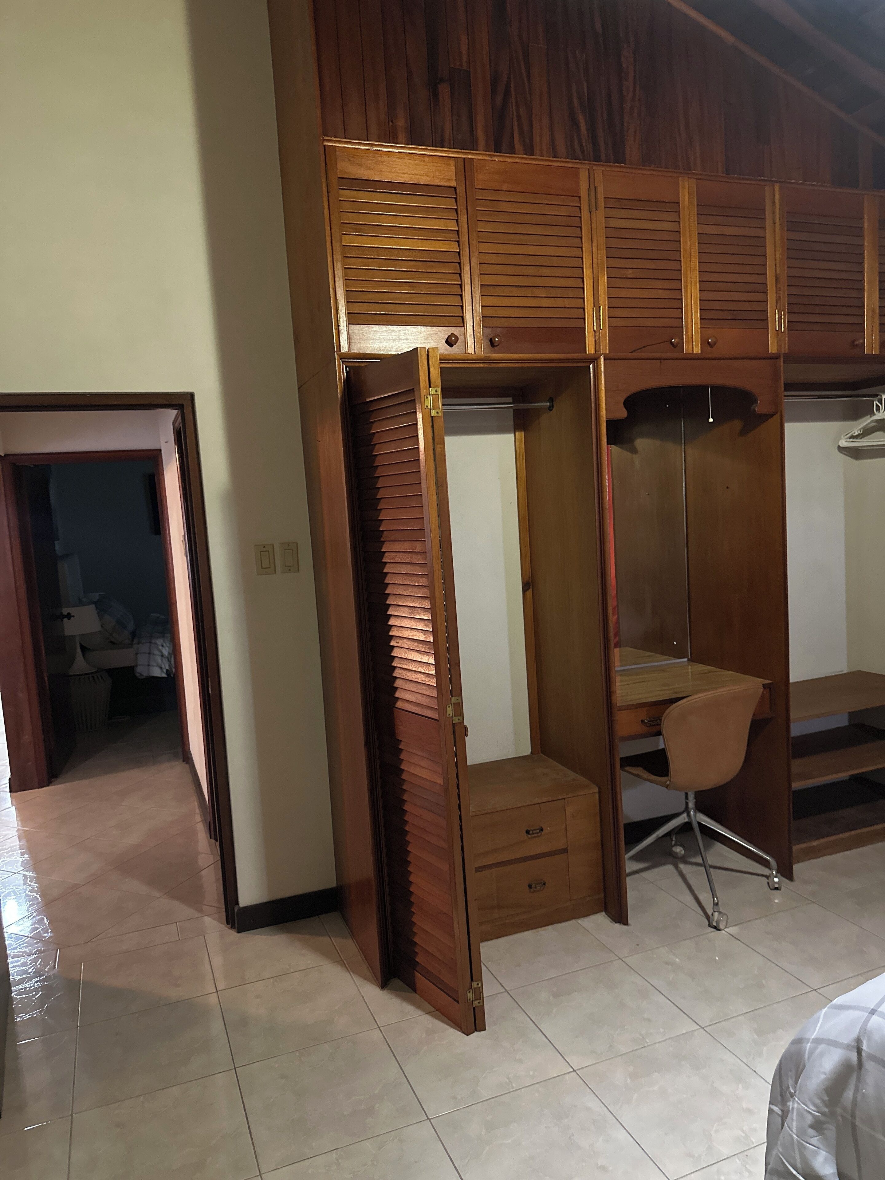 Une chambre à coucher avec une armoire en bois, un bureau et une chaise.