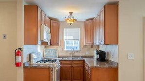 Una cucina con mobili in legno, un piano cottura a gas, un lavello e un lampadario.
