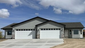 A two-story house with a garage, a stone accent wall, and a clear sky.