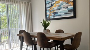 A dining area with a wooden table and six chairs, a potted plant, and a large abstract painting on the wall. - Stockbridge Quiet Hideaway (Stockbridge)