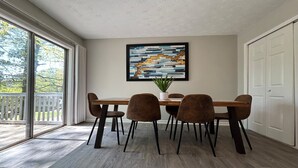 A dining area with a wooden table and four chairs, a potted plant, and a large abstract painting on the wall. - Stockbridge Quiet Hideaway (Stockbridge)