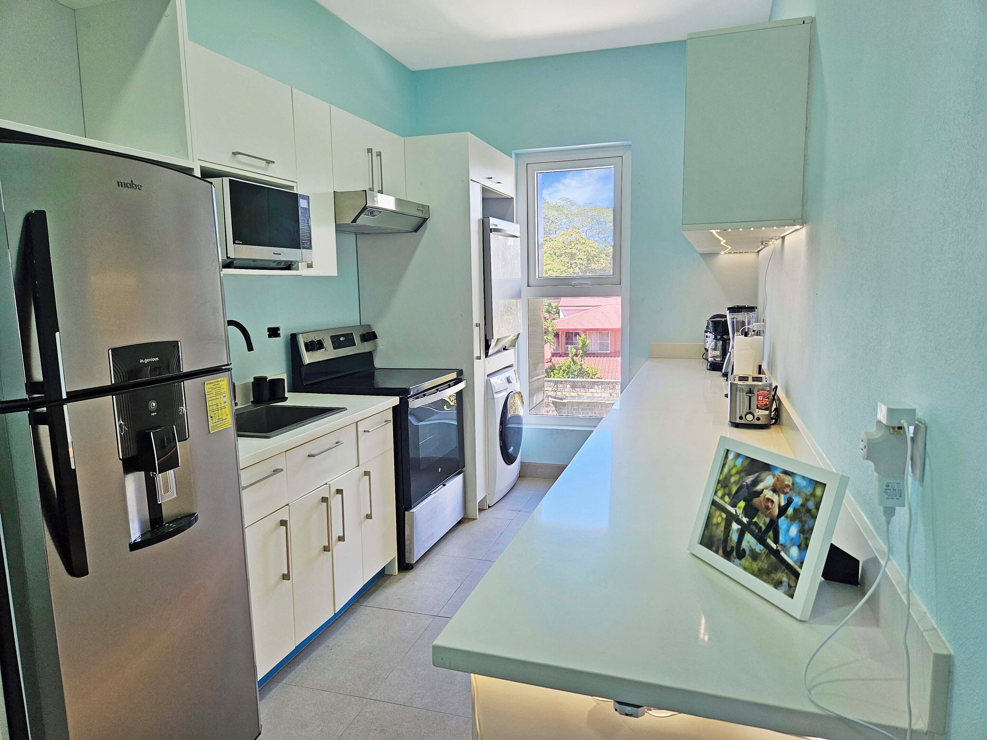 A compact kitchen with a refrigerator, microwave, stove, and washing machine.