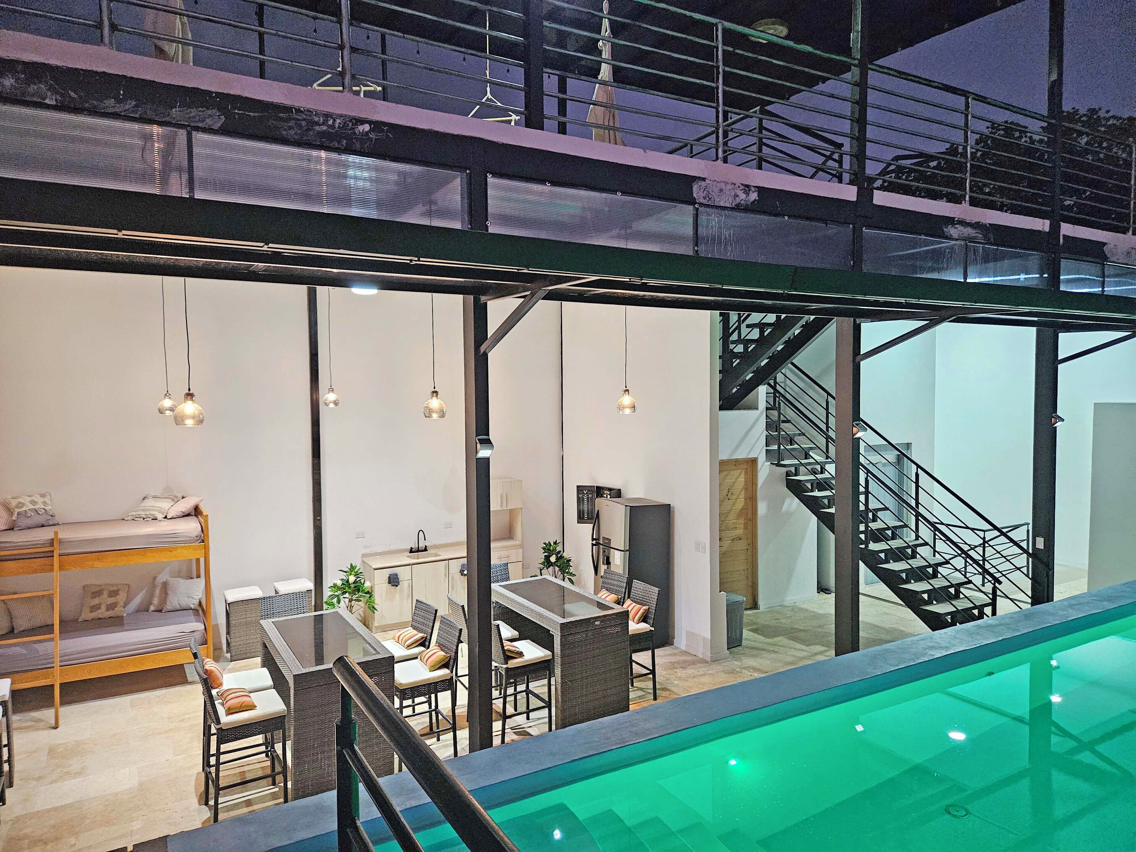A modern interior with a pool, a bunk bed, a dining area, and a staircase.