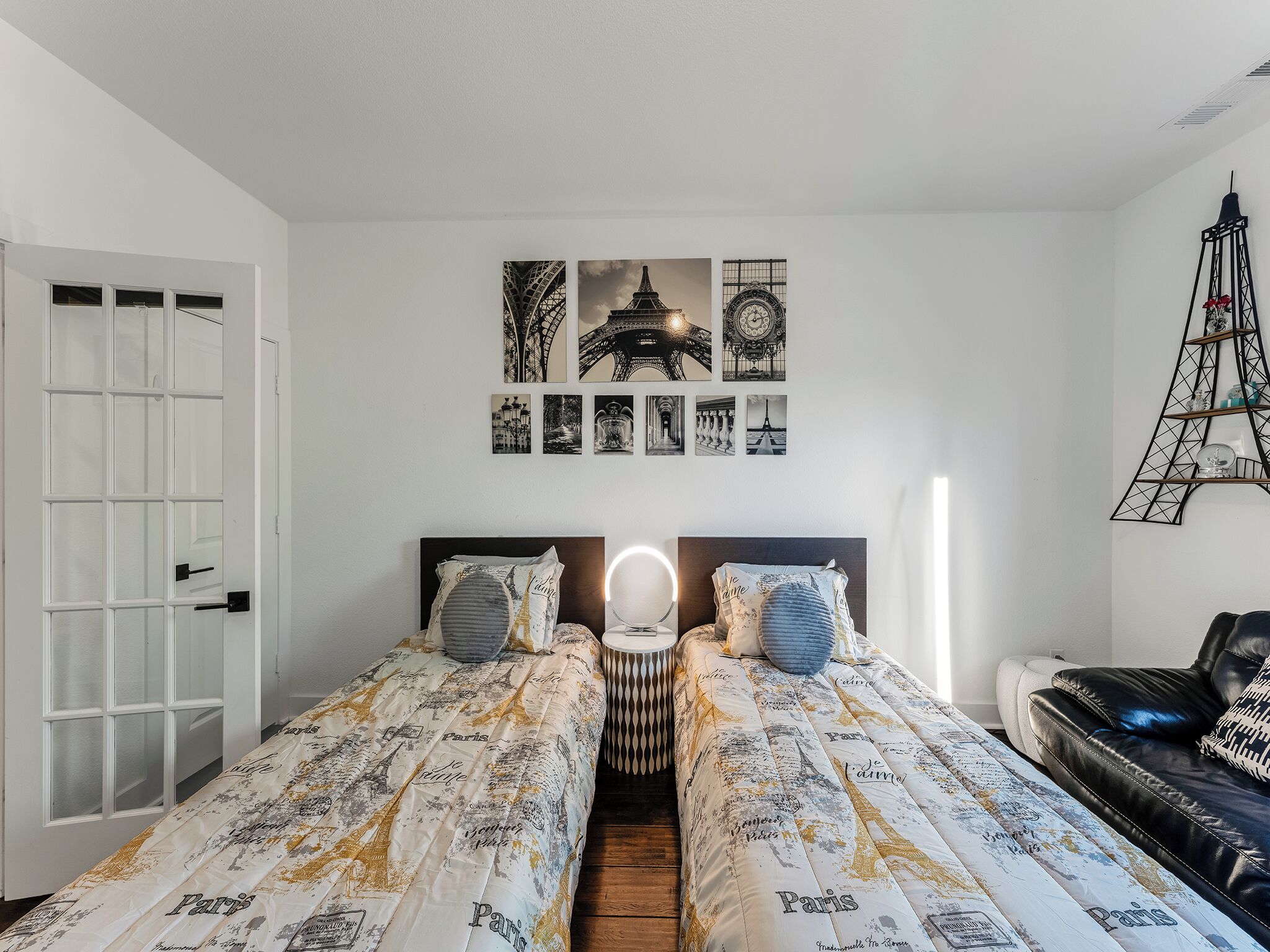 Una habitación con dos camas, un espejo y un sofá de cuero negro.