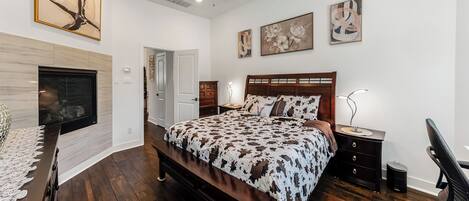 A bedroom with a bed, a ceiling fan, a TV, and artwork on the walls.