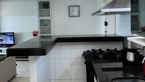 Una cocina moderna con encimera negra, electrodomésticos de acero inoxidable y horno empotrado.