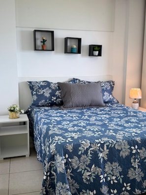 A bedroom with a bed, nightstands, a lamp, and wall-mounted planters.