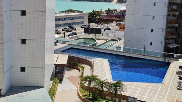 Un edificio de gran altura con zona de piscina, que incluye una terraza solárium y sillones de descanso.