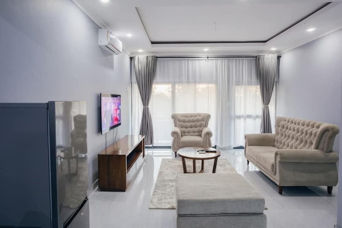 A modern living room with a flat-screen TV, a sofa, a chair, and a coffee table.