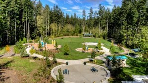 Un parque con césped circular, senderos peatonales y un pequeño pabellón.