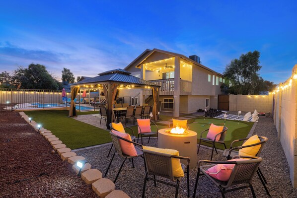 A backyard with a pool, outdoor seating, and a fire pit.