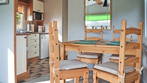 Une cuisine de taille réduite, dotée de meubles en bois, d’une table à manger et d’un luminaire suspendu.