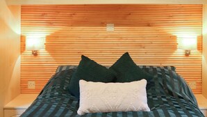 Un lit avec une literie à rayures, deux oreillers et une tête de lit en bois dotée d’un éclairage intégré.