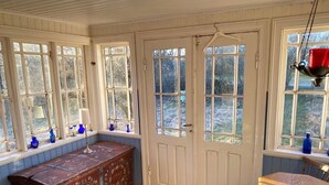 A room with a wooden bench, a table, and a door. - Charming Old Cottage in Scenic Southern Småland, Just Outside Markaryd | SE07057 (Markaryd)