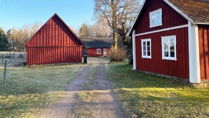 A rural setting with two red barns and a gravel path. - Charming Old Cottage in Scenic Southern Småland, Just Outside Markaryd | SE07057 (Markaryd)