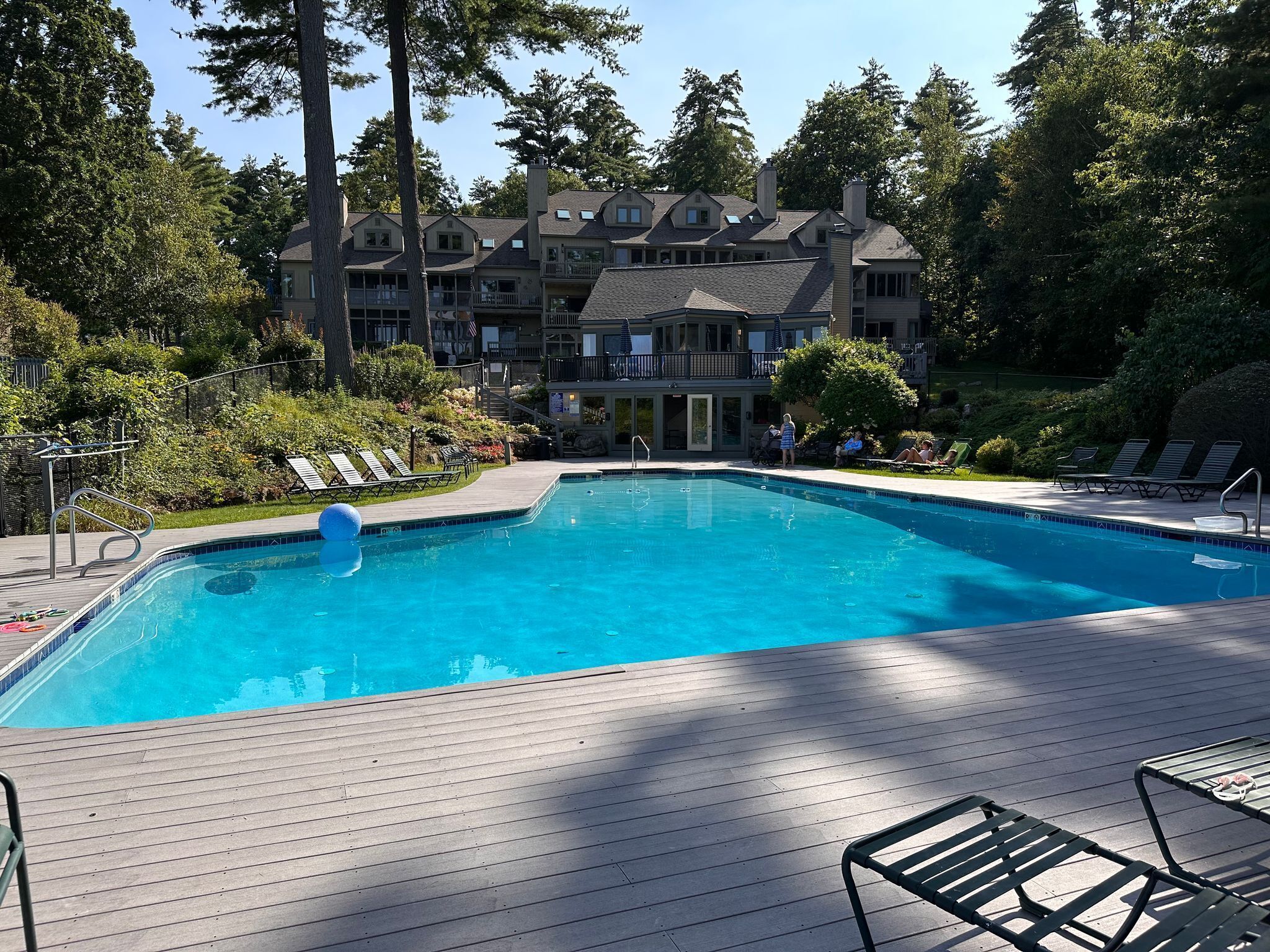 A swimming pool with lounge chairs and a wooden deck.