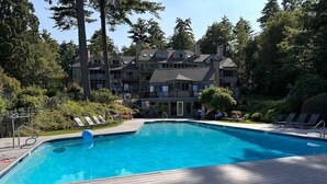 A swimming pool with lounge chairs and a wooden deck. - Lake Access-Pool-Beach-Tennis-Fireplace-Sunroom (Gilford)
