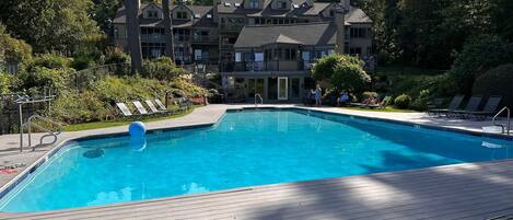 A swimming pool with lounge chairs and a wooden deck.