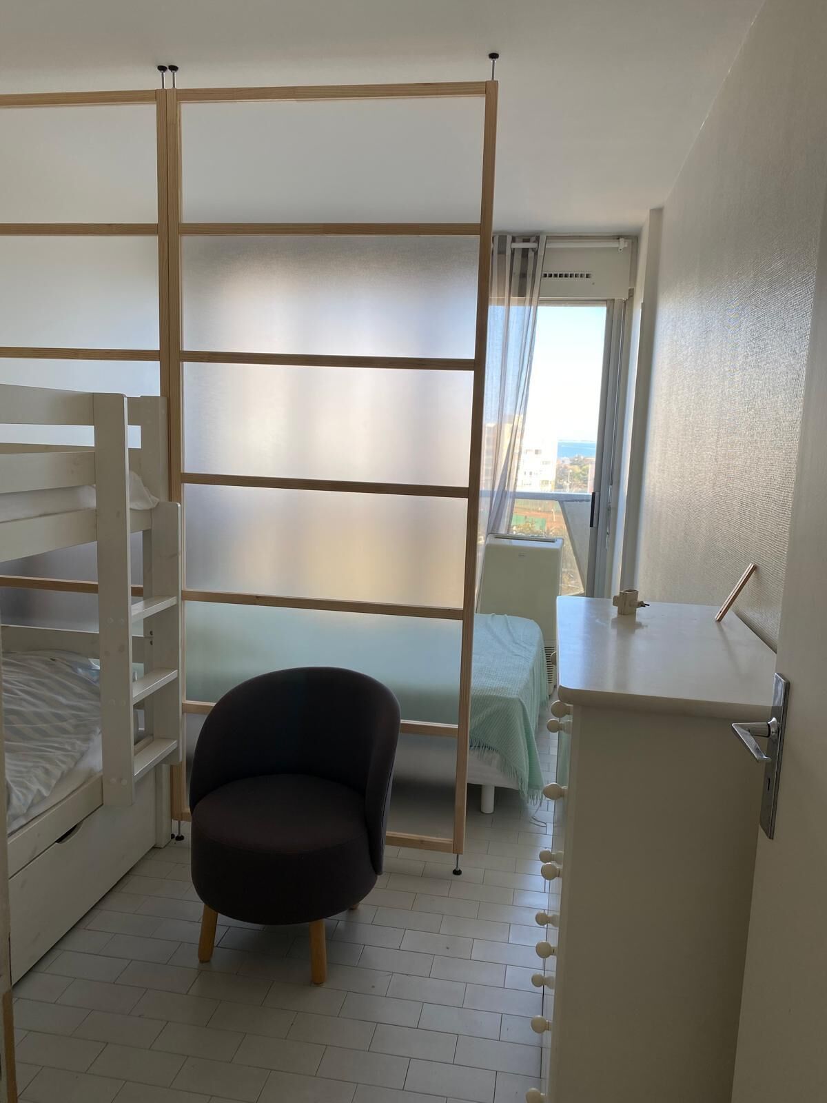Ein Schlafzimmer mit Etagenbett, einem Sessel, einem Schreibtisch und einem Fenster mit Blick.