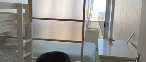 Ein Schlafzimmer mit Etagenbett, einem Sessel, einem Schreibtisch und einem Fenster mit Blick.