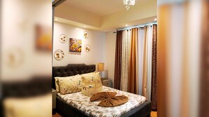 Una habitación de hotel con cama, mesita de noche, lámpara y cortinas.