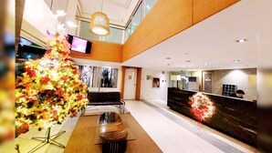 Un moderno vestíbulo de hotel con un gran árbol de Navidad iluminado, zona de estar y una recepción.