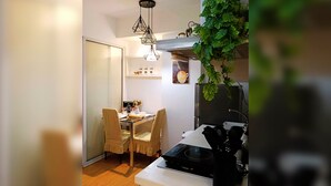 Una cocina compacta con zona de comedor, refrigerador, estufa y una planta colgante.
