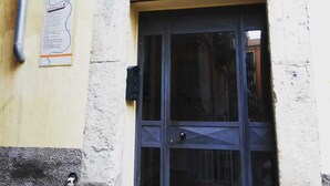 Una entrada de edificio con una puerta azul oscuro, un ventanal arqueado arriba y una pequeña señal en la pared.