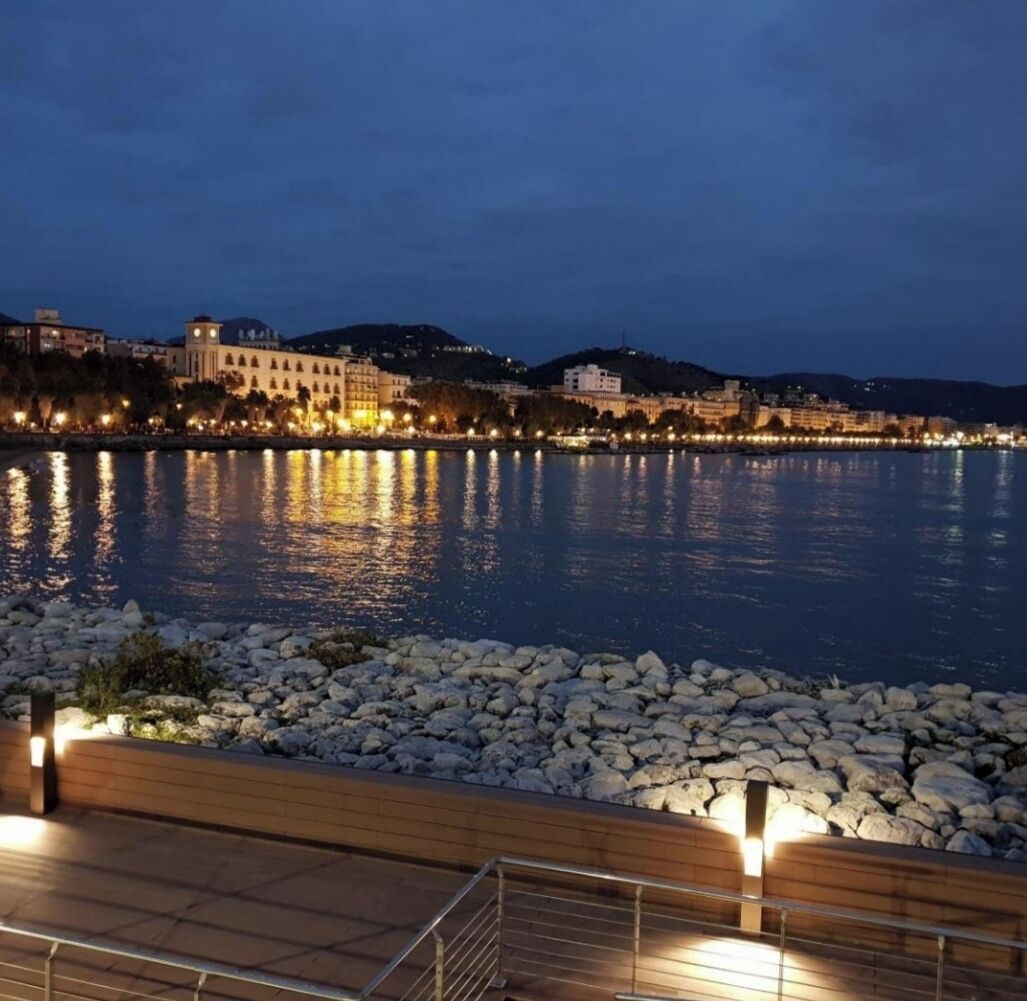 A waterfront promenade with a stone balustrade and a wooden deck.