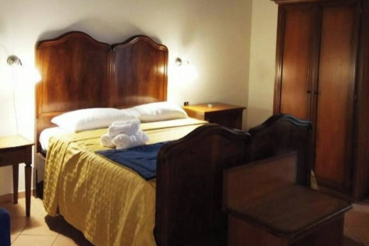 Une chambre à coucher avec un lit en bois, des tables de chevet, une armoire et un luminaire suspendu.