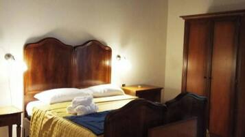 A bedroom with a wooden bed, bedside tables, a wardrobe, and a hanging light fixture.