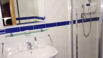 A bathroom with a white sink, a glass shower enclosure, and blue-tiled walls.