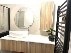 Une salle de bain moderne avec un lavabo blanc, un miroir rond et un meuble-lavabo en bois.