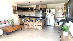 Een moderne keuken met barstoelen, een eettafel en een aan de muur bevestigde televisie.