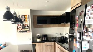 Een moderne keuken met houten kasten, een zwarte koelkast en hanglampen.