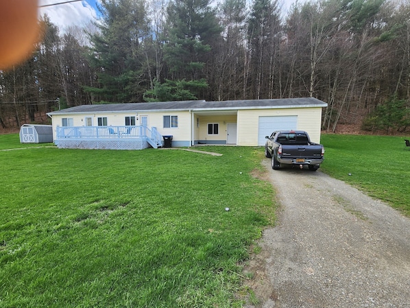 A single-story house with a covered porch, a gravel driveway, and a truck parked in front.