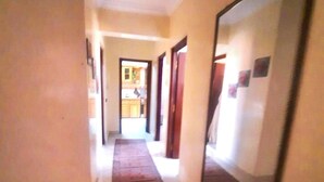 A narrow hallway with a carpet leading to a kitchen area. - Charming 2-bedroom apartment with AC, WiFi in delightful Marrakech (Marrakech)