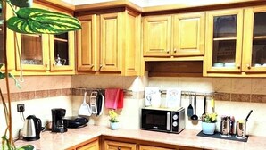A kitchen with wooden cabinets, a microwave, a kettle, and a plant. - Charming 2-bedroom apartment with AC, WiFi in delightful Marrakech (Marrakech)