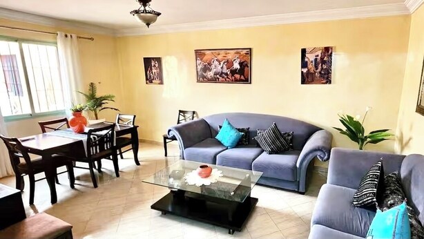 A living room with a sofa, a coffee table, and a dining table. - Charming 2-bedroom apartment with AC, WiFi in delightful Marrakech (Marrakech)