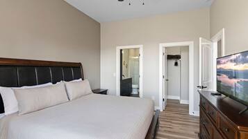 Un dormitorio con una cama grande, televisión, ventilador de techo y vestidor.