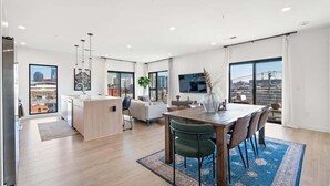 A modern apartment with a kitchen, dining area, and living room, featuring large windows and a city view. - Cuddly Cactus for 12|Wraparound Balcony, Pool, Gym (Nashville)