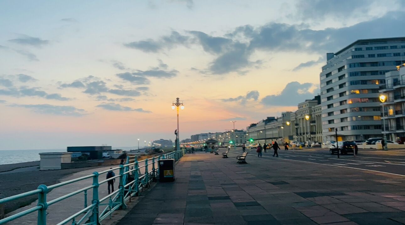 A waterfront promenade with benches, street lamps, and buildings along the side.