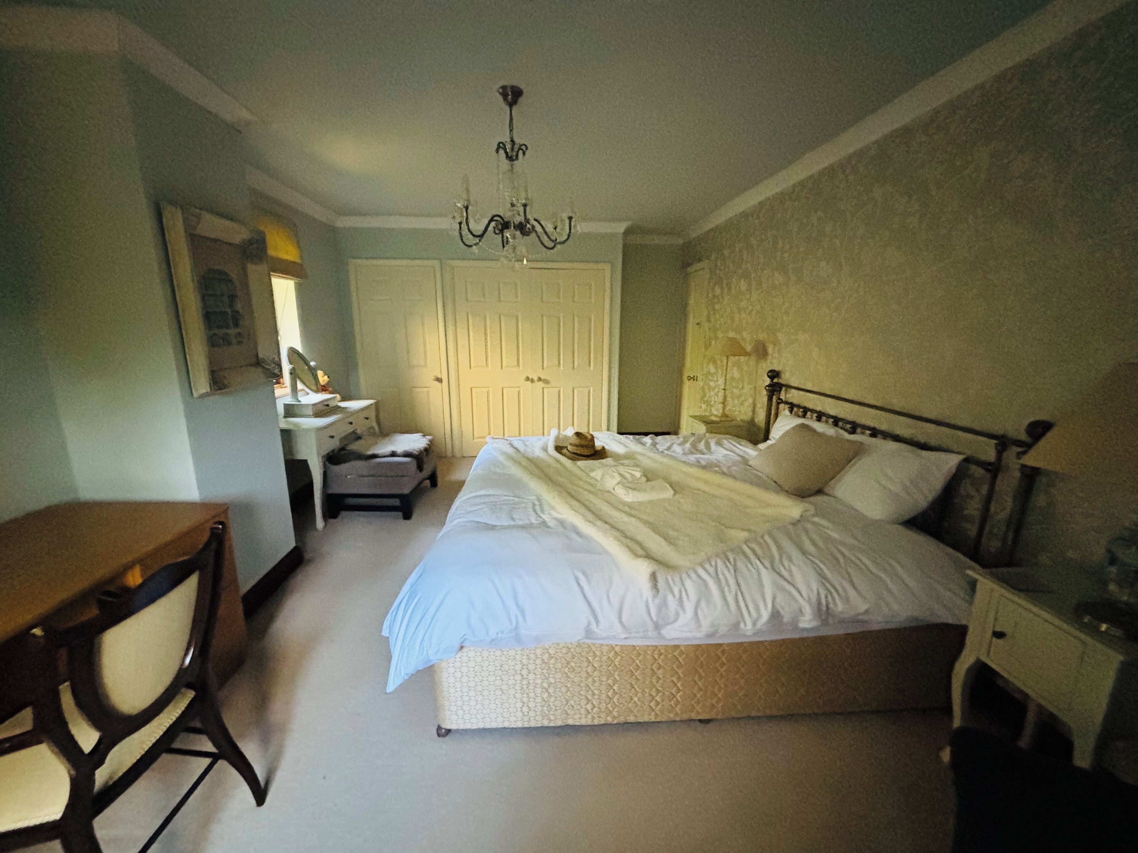 A bedroom with a bed, bedside table, chair, desk, and a wardrobe.