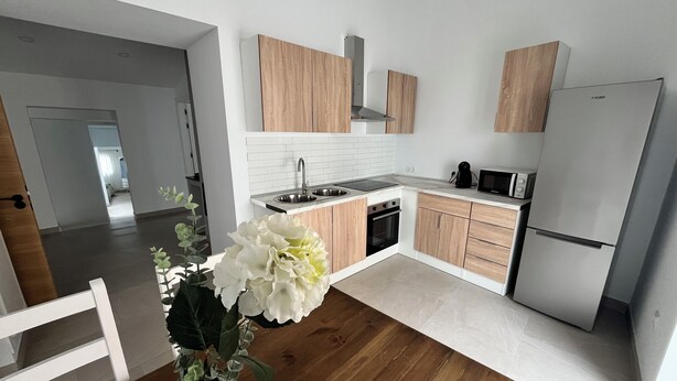 A modern kitchen with wooden cabinets, a stainless steel sink, and a built-in oven.